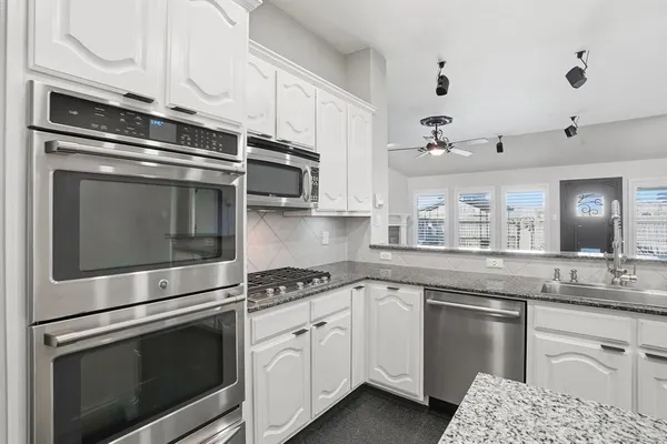 a kitchen with granite countertop white cabinets and a sink