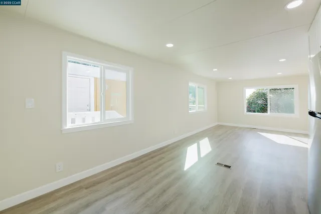 an empty room with wooden floor and windows
