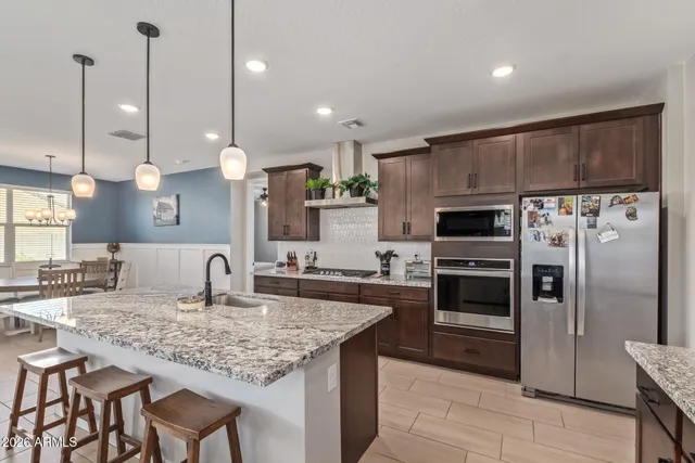 a kitchen with stainless steel appliances kitchen island granite countertop a sink stove and refrigerator