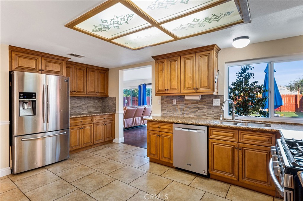 16398 Heather Glen Road Moreno Valley, CA 92551 - Photo 21 of 74 a kitchen with stainless steel appliances granite countertop a refrigerator and a sink
