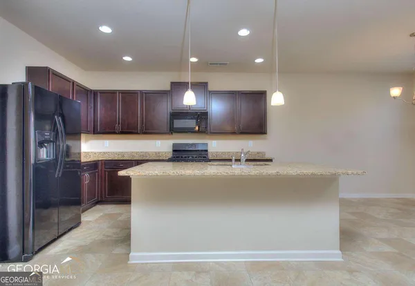 a kitchen with stainless steel appliances granite countertop a refrigerator a sink and a stove