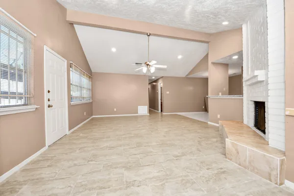 a view of an empty room with kitchen and a window