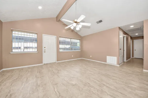 an empty room with windows and ceiling fan
