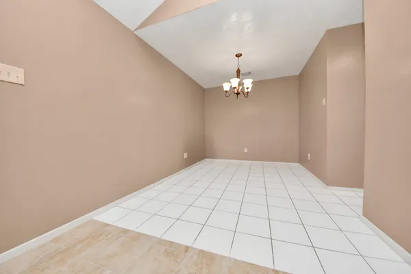 a view of an empty room with chandelier fan
