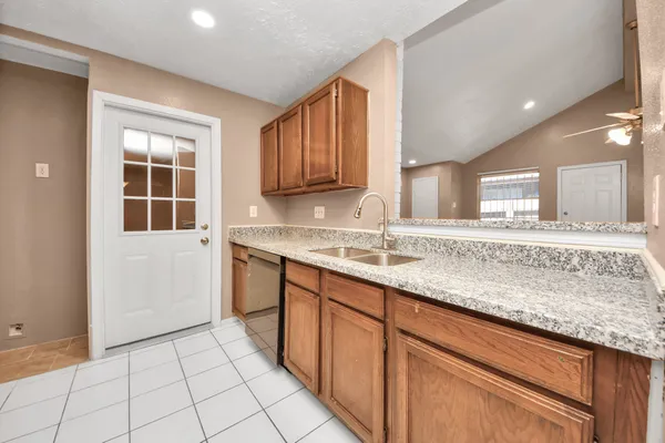 a kitchen with granite countertop a sink stainless steel appliances white cabinets and a window