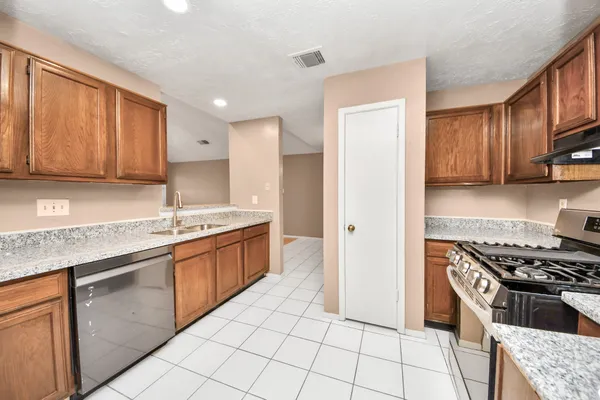a kitchen with stainless steel appliances granite countertop a stove a sink and a refrigerator