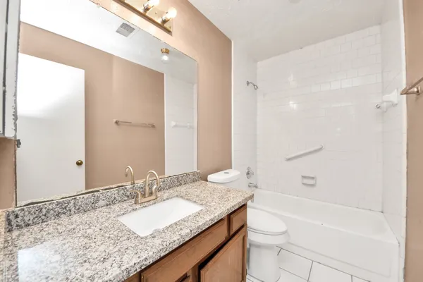 a bathroom with a granite countertop sink a toilet and shower