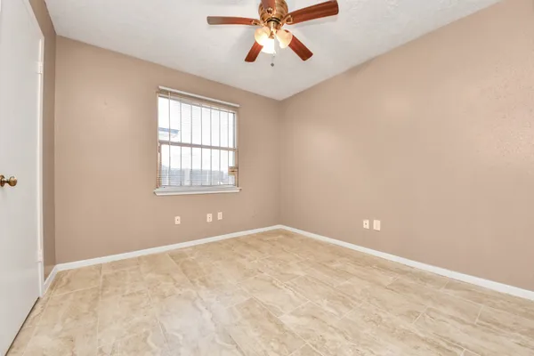 an empty room with chandelier fan and windows