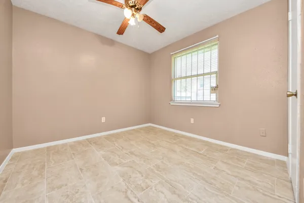an empty room with windows and fan