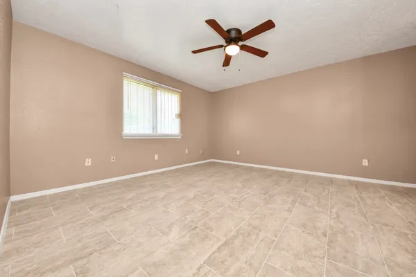an empty room with a ceiling fan and window