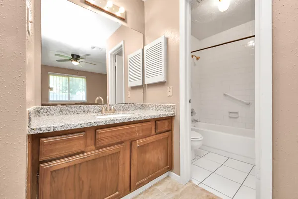 a bathroom with a granite countertop sink a mirror and a bathtub