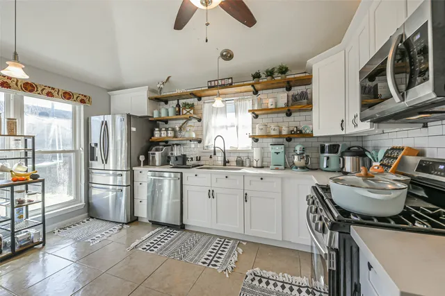 a kitchen with granite countertop a refrigerator stove top oven and sink