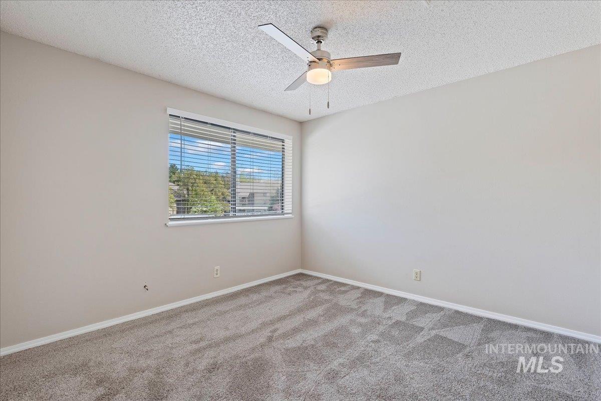 3611 South Gekeler Lane, Unit 124 Boise, ID 83706 - Photo 14 of 27 Empty room with light carpet, a textured ceiling, and ceiling fan