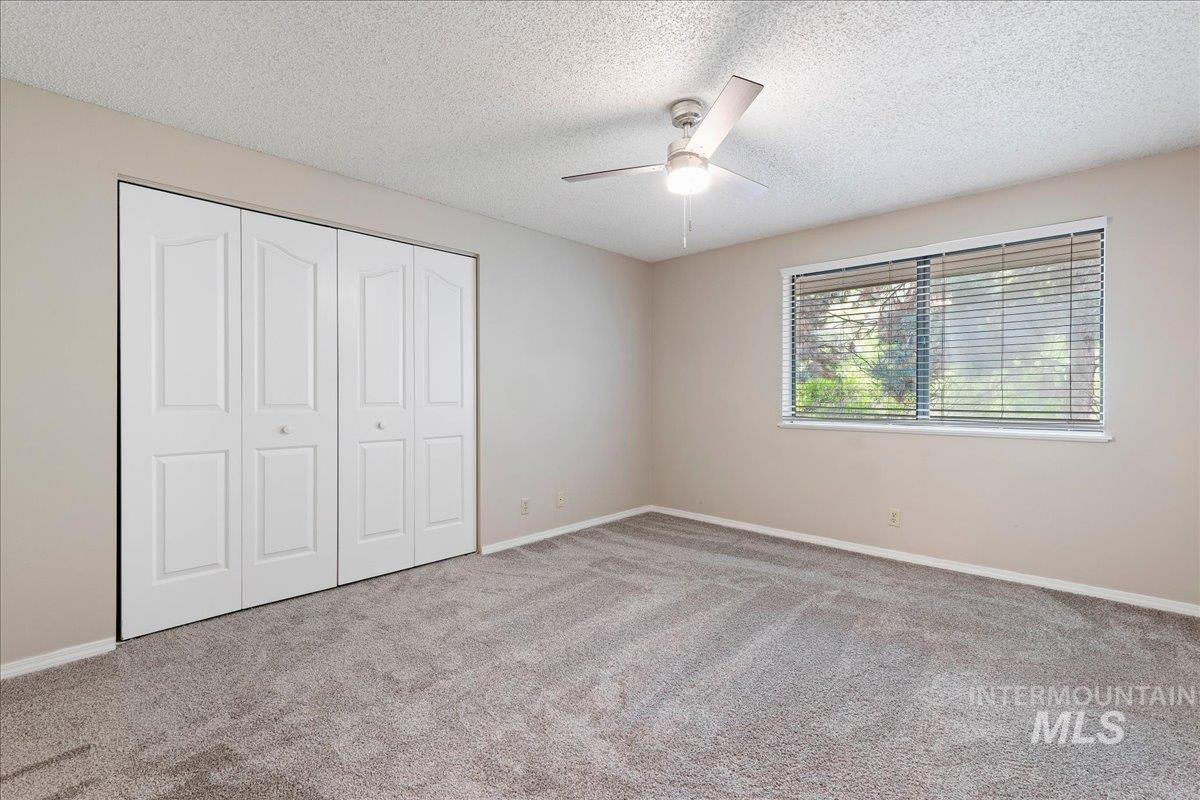 3611 South Gekeler Lane, Unit 124 Boise, ID 83706 - Photo 15 of 27 Unfurnished bedroom with a textured ceiling, a closet, carpet floors, and ceiling fan