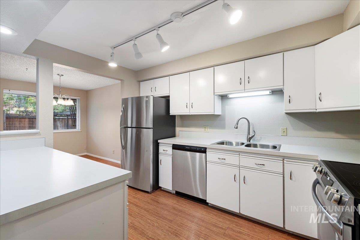 3611 South Gekeler Lane, Unit 124 Boise, ID 83706 - Photo 8 of 27 Kitchen featuring white cabinets, light countertops, stainless steel appliances, and track lighting