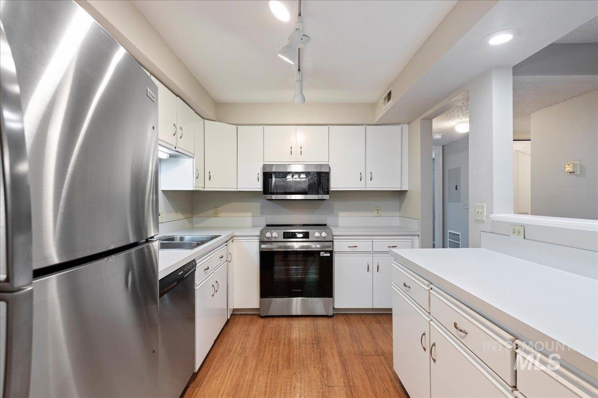 3611 South Gekeler Lane, Unit 124 Boise, ID 83706 - Photo 9 of 27 Kitchen with stainless steel appliances, white cabinetry, light countertops, light wood finished floors, and rail lighting