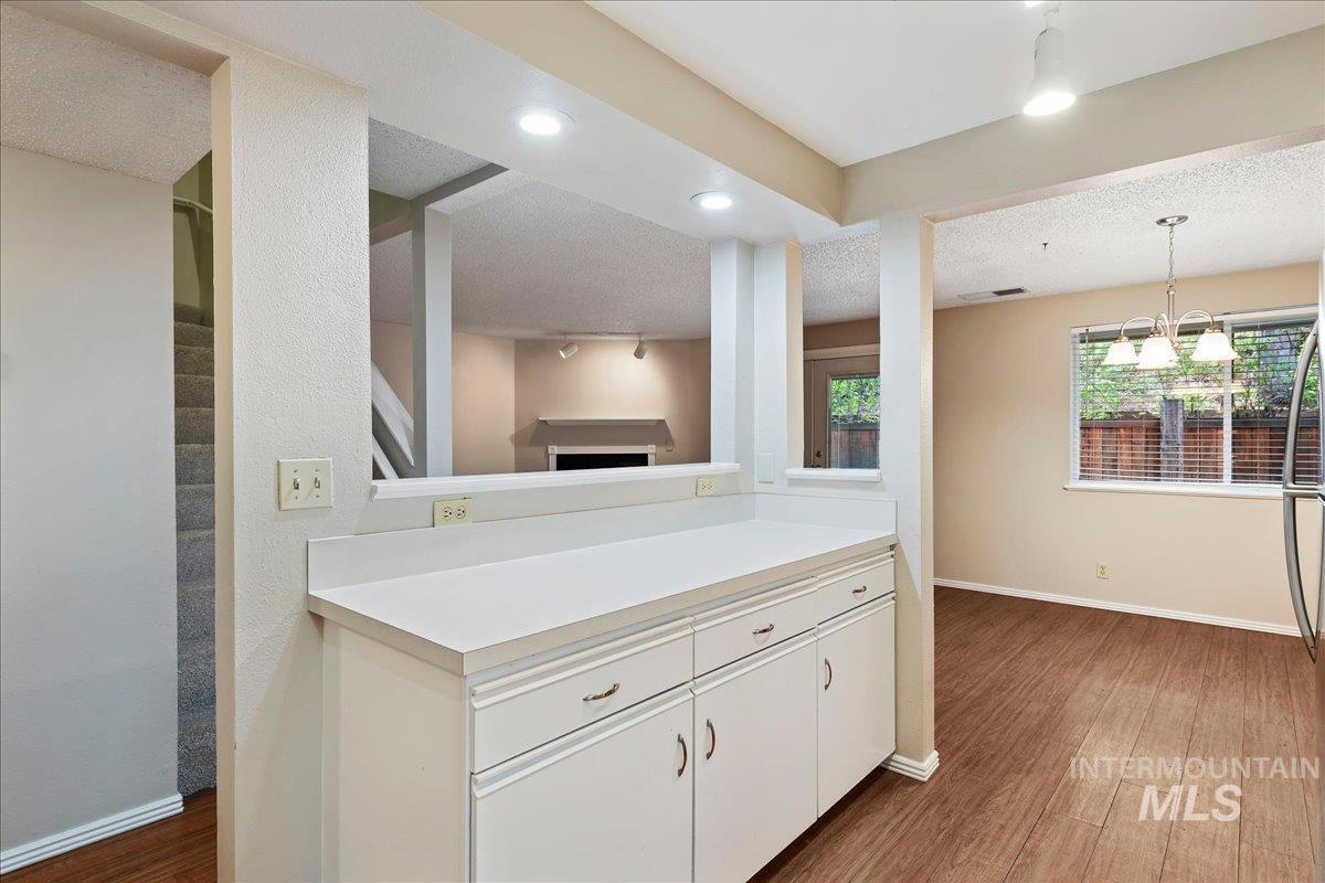 3611 South Gekeler Lane, Unit 124 Boise, ID 83706 - Photo 10 of 27 Kitchen with light countertops, dark wood-style floors, white cabinets, a textured ceiling, and suspended lighting