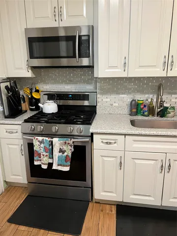 a kitchen with stainless steel appliances granite countertop white cabinets and a stove a oven with white countertops