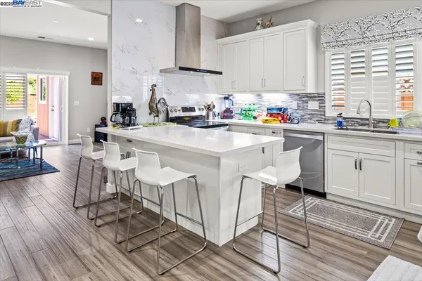 a kitchen with stainless steel appliances granite countertop a table chairs sink and cabinets