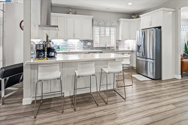 a kitchen with stainless steel appliances granite countertop a stove top oven a refrigerator and cabinets