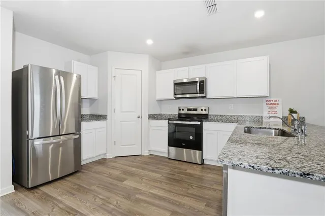 a kitchen with granite countertop a refrigerator and a stove top oven