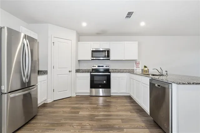 a kitchen with granite countertop a refrigerator and a stove top oven