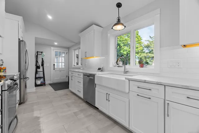 a kitchen with white cabinets and window