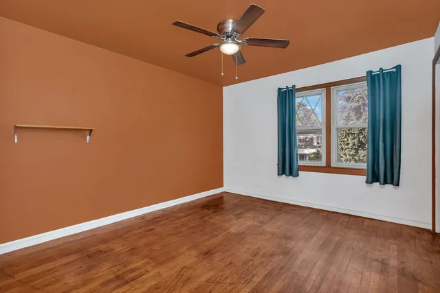 a view of an empty room with window and chandelier fan