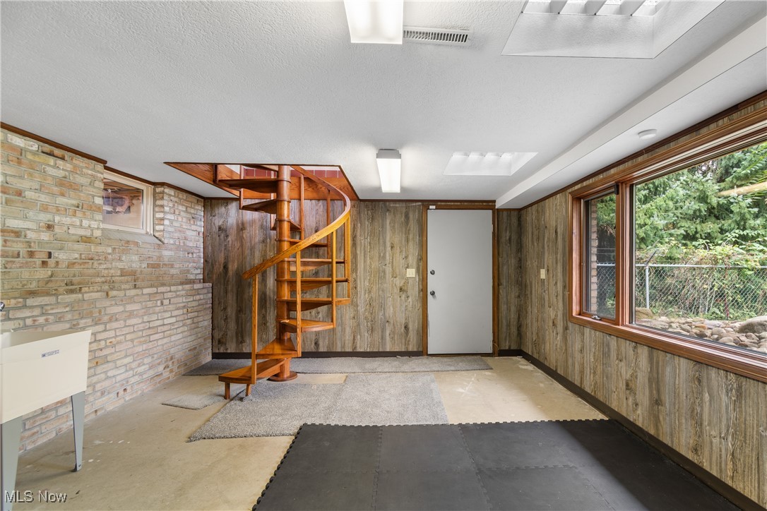 2317 Raintree Street Northeast Canton, OH 44705 - Photo 12 of 40 Below grade area with wood walls, stairs, brick wall, and a textured ceiling