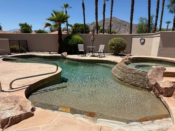 a view of a swimming pool with a yard and palm trees