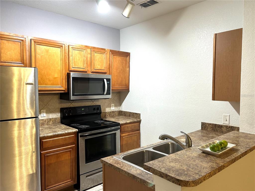 6137 Metrowest Boulevard, Unit 307 Orlando, FL 32835 - Photo 9 of 28 a kitchen with stainless steel appliances granite countertop a sink stove and refrigerator
