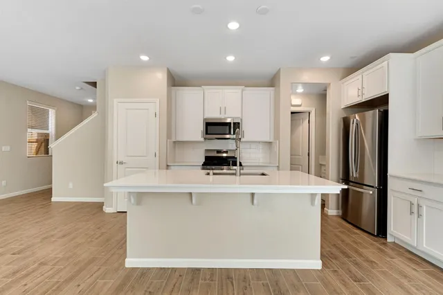 a kitchen with kitchen island white cabinets and stainless steel appliances