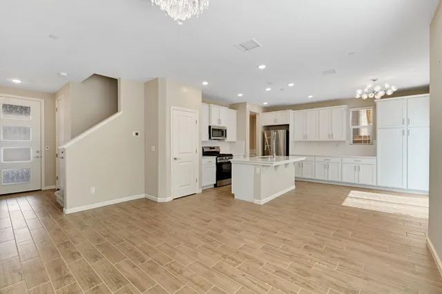 a view of a kitchen with kitchen island wooden floor center island and stainless steel appliances