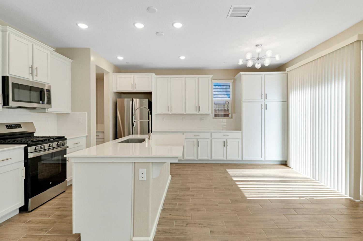 1116 Encore Way West Madera, CA 93636 - Photo 10 of 35 a kitchen with stainless steel appliances granite countertop a stove a sink and a refrigerator