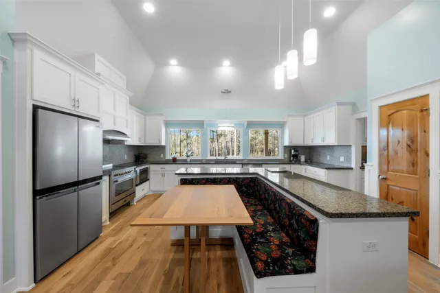 a large kitchen with a center island wooden floor and stainless steel appliances