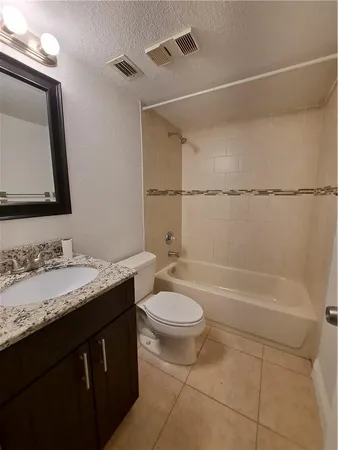 a bathroom with a granite countertop sink a toilet and bathtub