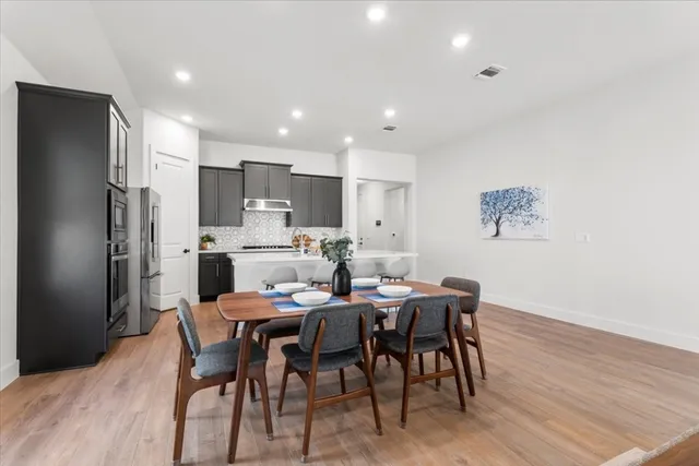 a kitchen with stainless steel appliances a dining table chairs and wooden floor
