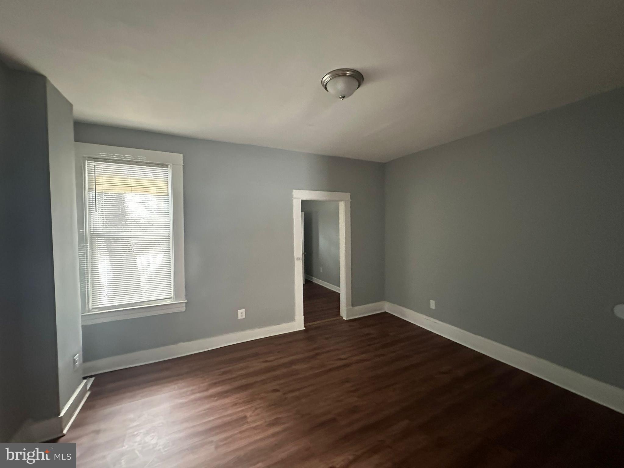 2806 Violet Avenue Baltimore, MD 21215 - Photo 6 of 10 an empty room with wooden floor and windows