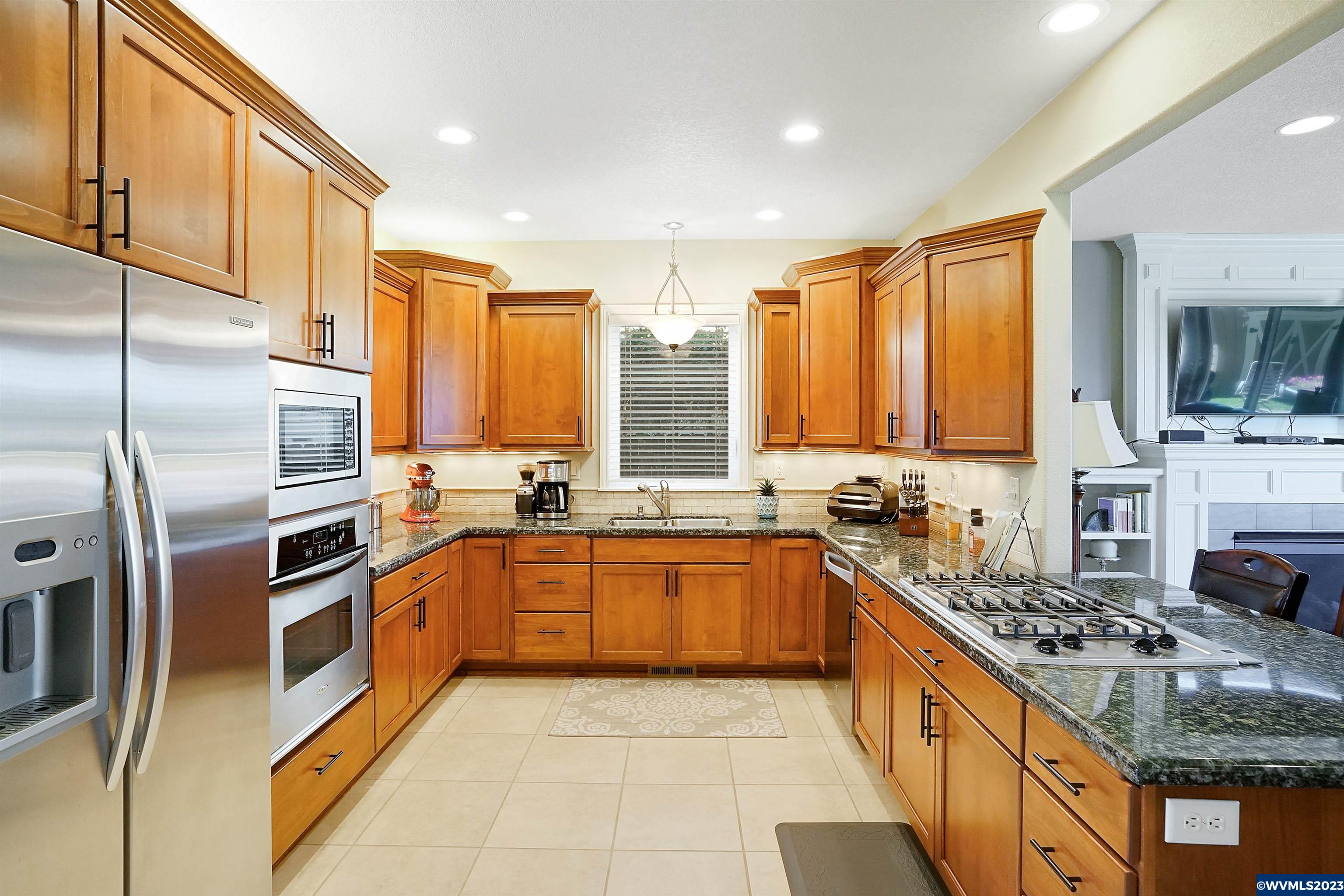 306 Northwest Reed Lane Dallas, OR 97338 - Photo 14 of 42 a large kitchen with stainless steel appliances granite countertop a stove top oven a sink dishwasher a refrigerator and cabinets with wooden floor