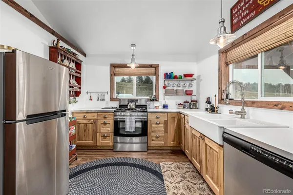 a kitchen with stainless steel appliances granite countertop a refrigerator a sink dishwasher a stove and white countertops with wooden floor