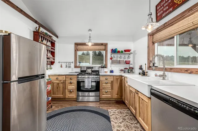 a kitchen with stainless steel appliances granite countertop a refrigerator a sink dishwasher a stove and white countertops with wooden floor