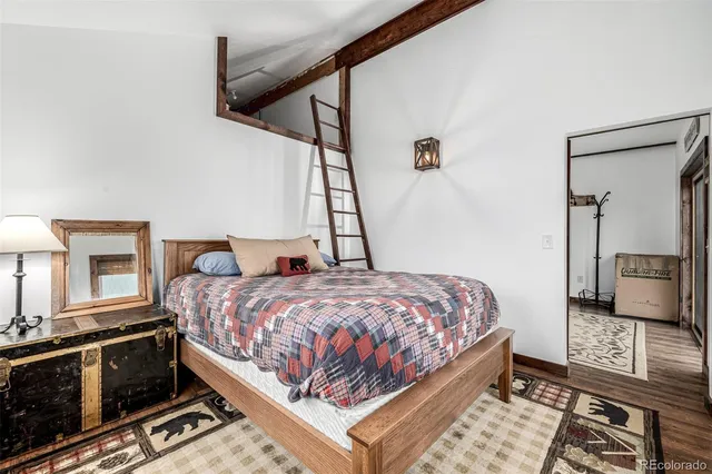 a bedroom with a bed next to a window with wooden floor