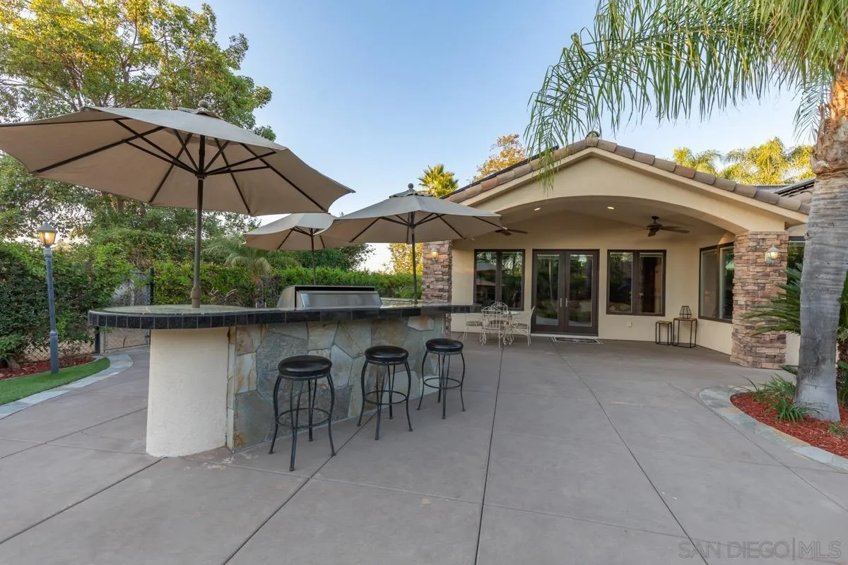 14401 Sandhill Road Poway, CA 92064 - Photo 48 of 75 a backyard of a house with table and chairs under an umbrella