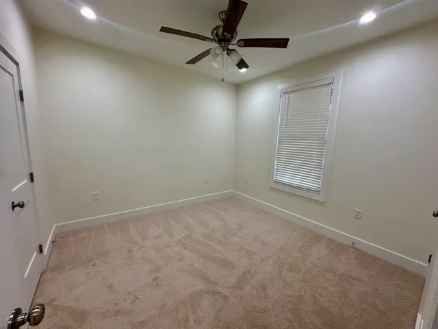 an empty room with windows and fan