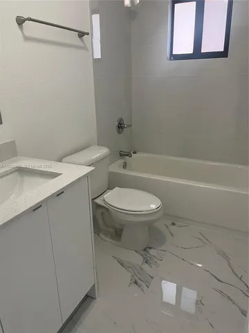 a white toilet sitting next to a bathroom sink and vanity