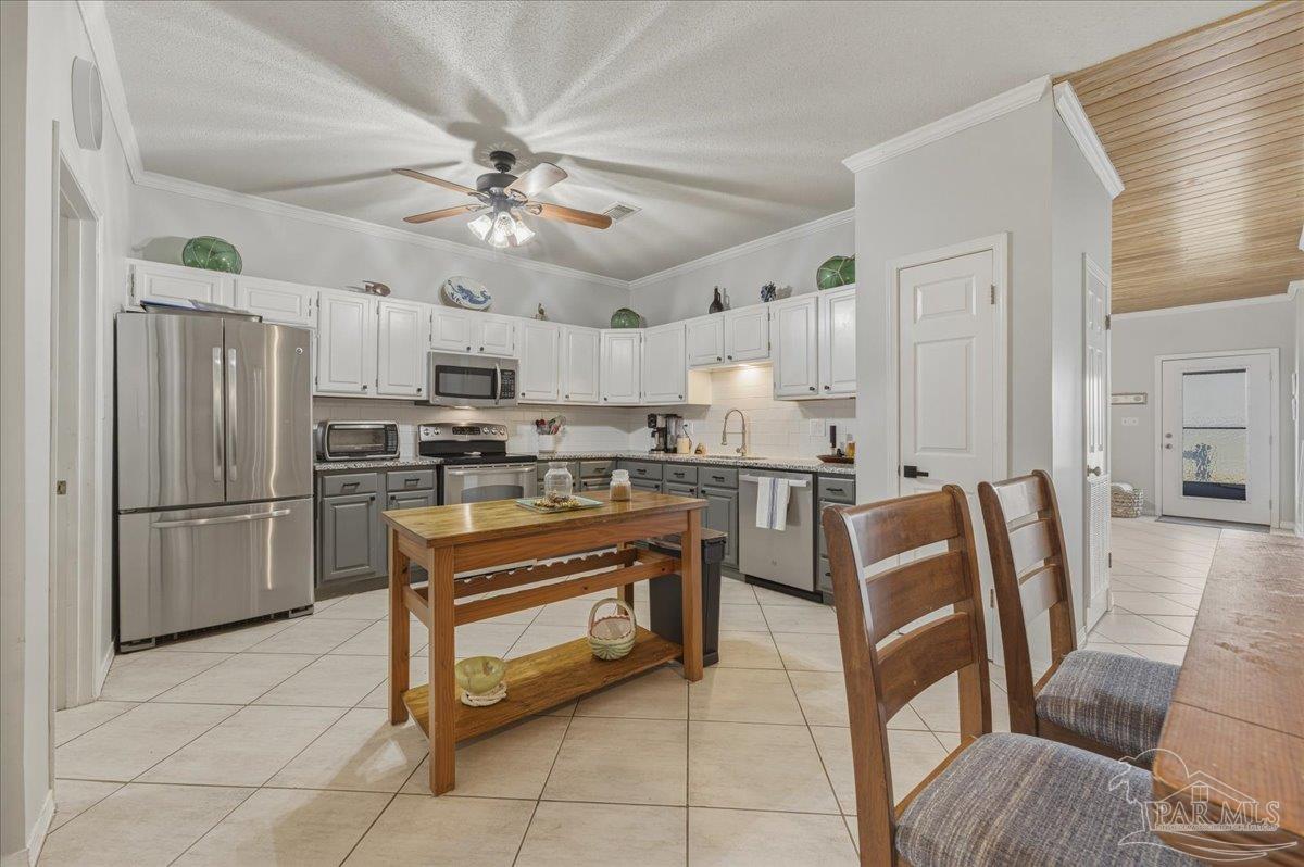 26063 Canal Road, Unit 3F Orange Beach, AL 36561 - Photo 27 of 72 a kitchen with stainless steel appliances granite countertop a refrigerator a stove a sink a dining table and chairs with wooden floor