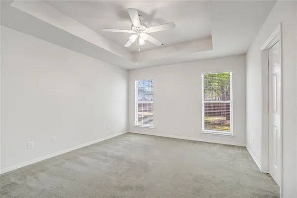 an empty room with windows and ceiling fan