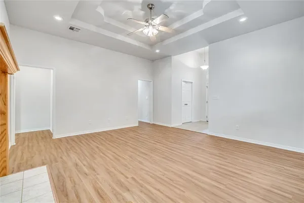 an empty room with wooden floor and fan