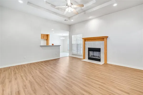 a view of an empty room with wooden floor and a fireplace