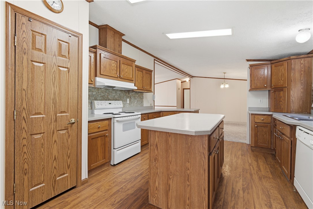 60602 Shaw Road Cambridge, OH 43725 - Photo 10 of 41 Kitchen featuring crown molding, light countertops, white appliances, dark wood finished floors, and decorative backsplash